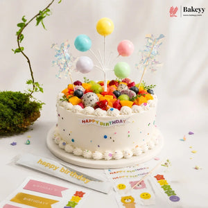 Colorful birthday cake with balloons and decorations on a white surface, featuring the Bakeyy brand.