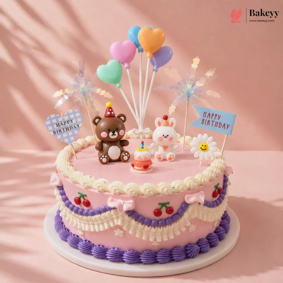 Decorative birthday cake with teddy bear, cloud, and cherry designs on a pink background.