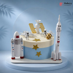 Space-themed cake with rocket models and astronaut figures on a blue background