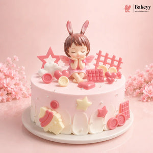 Pink cake with a decorative figure of a girl with bunny ears on a pink background, featuring the brand 'Bakeyy'.