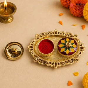 Decorative gold tray with red and multicolored powder, surrounded by Diwali decorations on a beige background.