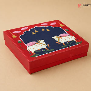 A square red gift box with a lid featuring a detailed illustration of two white cows with pink lotus flowers on a beige background.