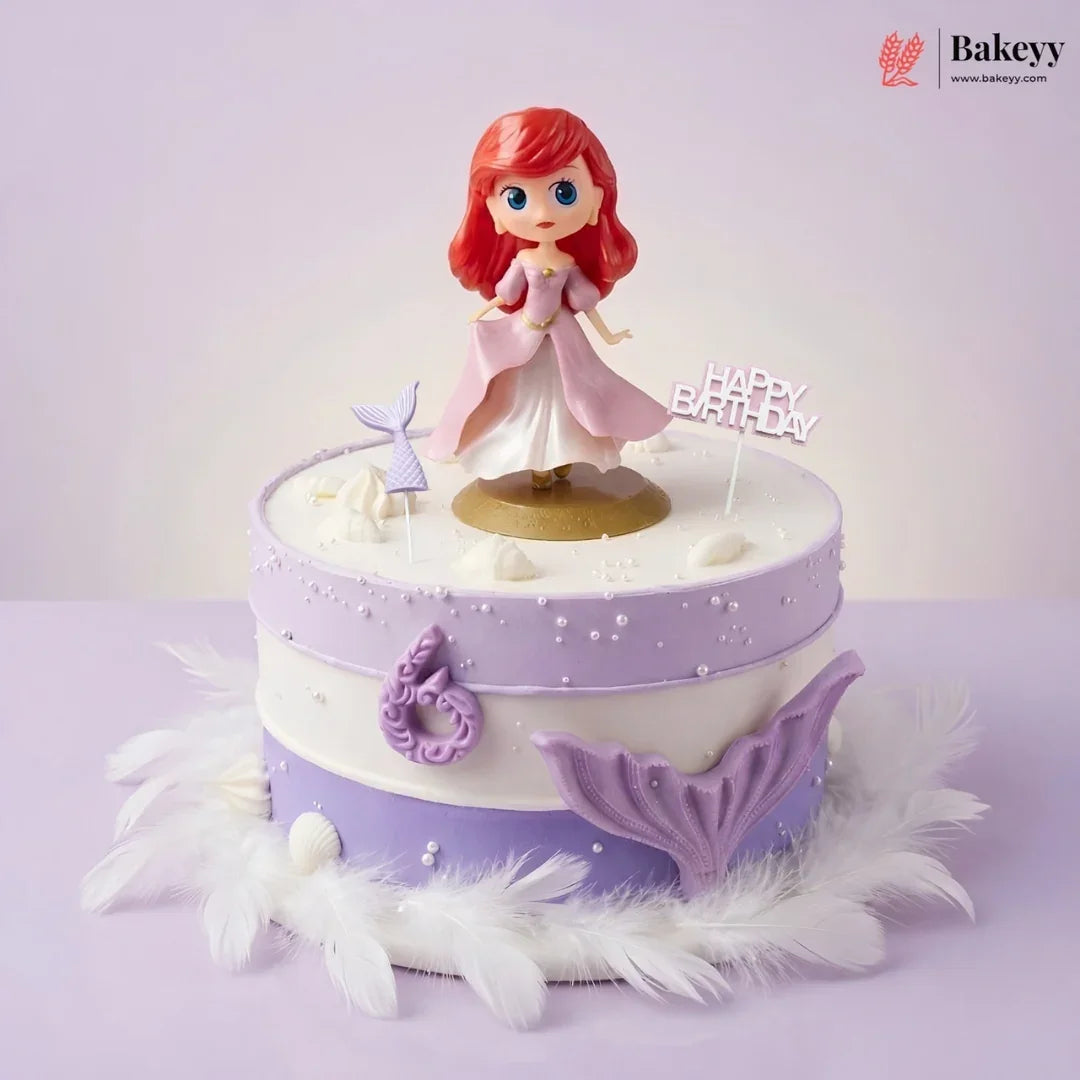 Decorative cake with a mermaid figurine and 'Happy Birthday' topper on a light purple background.