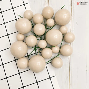 A cluster of glossy, beige faux pearlescent decorative beads with green stems, arranged on a split background of black-and-white checkered tiles and white wood planks. A 'flakeyy' brand logo is visible in the top right corner.