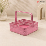 Pink metal basket with decorative handle on a beige surface, featuring the Bakey brand.