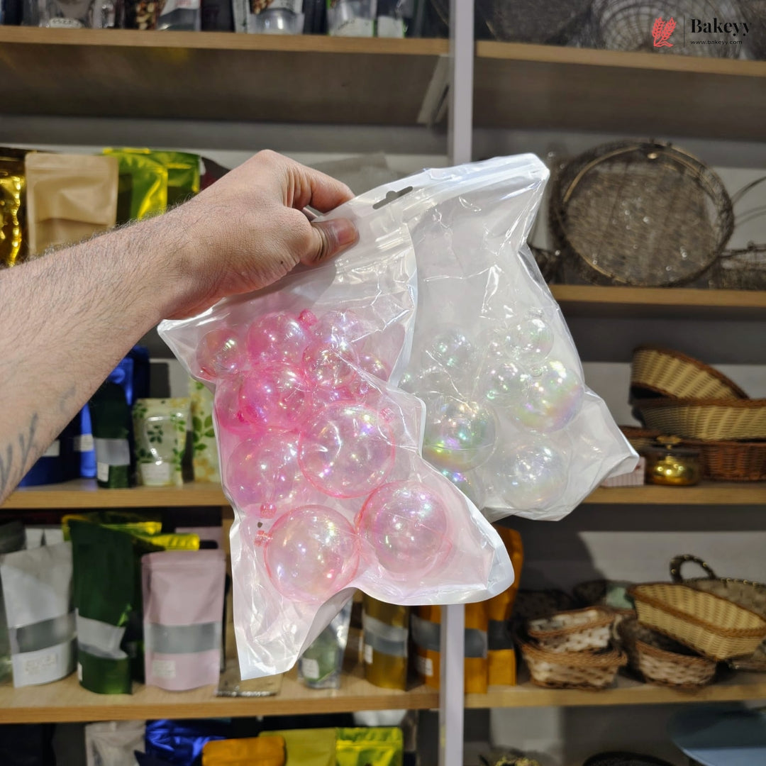 Hand holding a bag of pink and clear gelatinous balls in front of a shelf with various items.