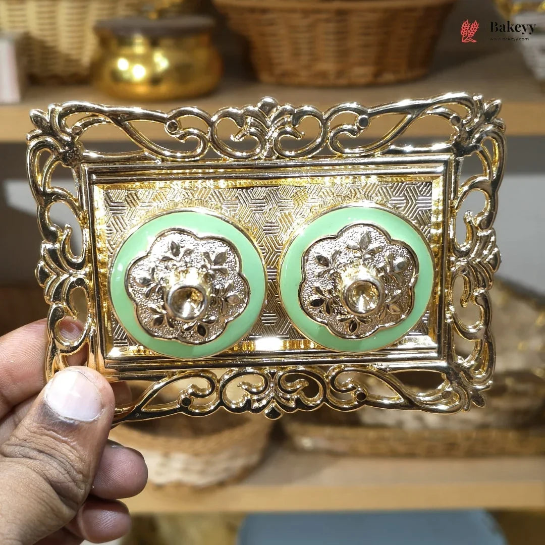 Decorative gold and green box held by a hand with blurred background