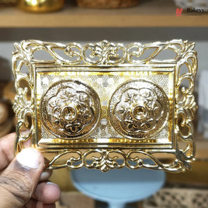 Decorative gold metal box held by a hand with a blurred background