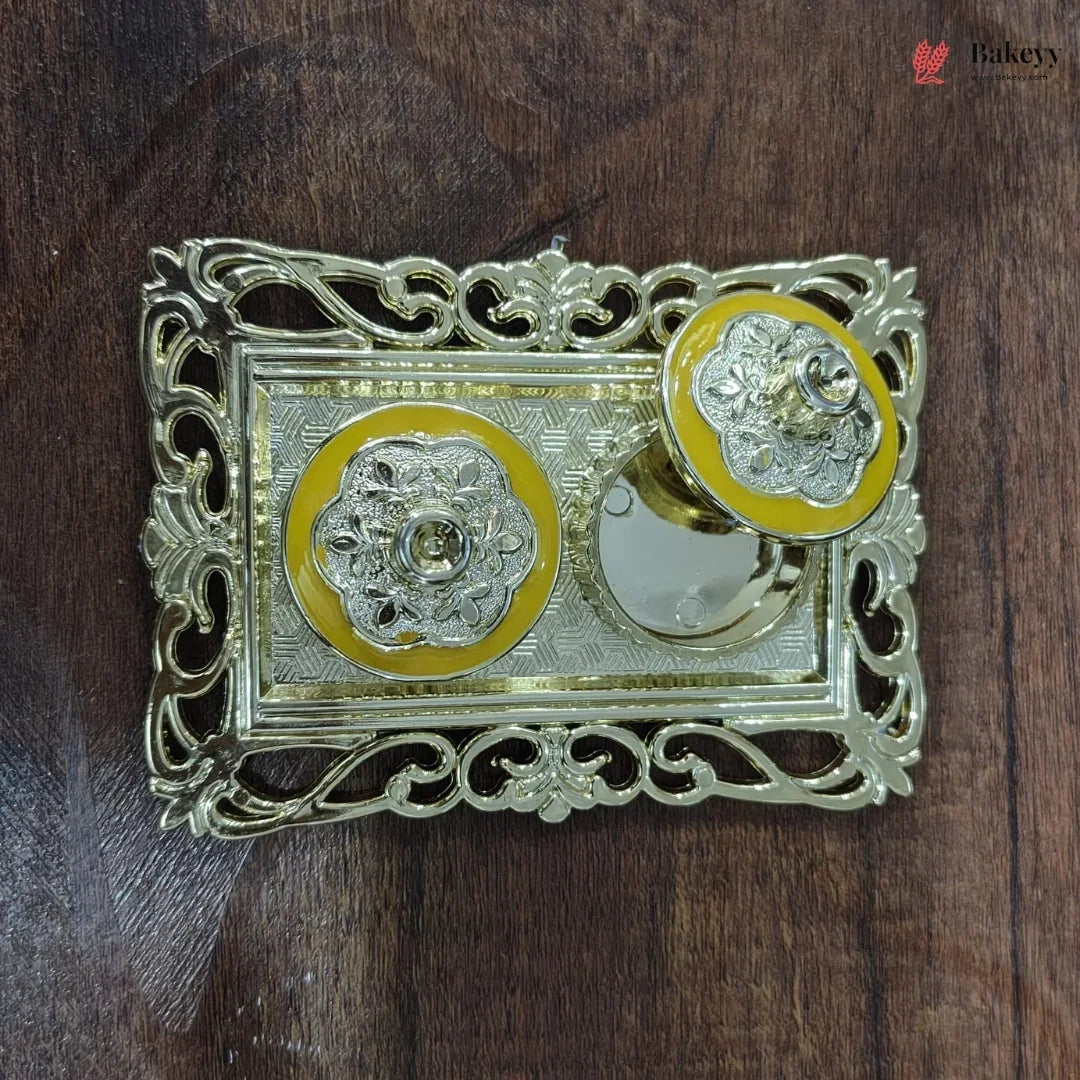 Decorative metal object with yellow and silver design on a wooden surface