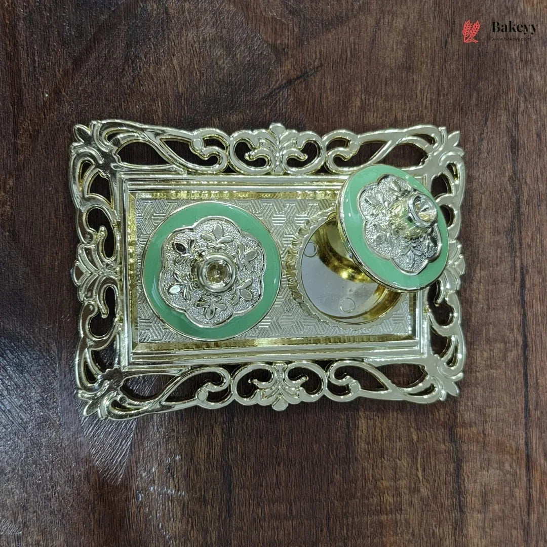 Decorative metal object with green circular designs on a wooden surface