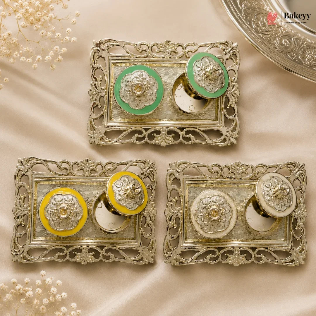 Decorative metal boxes with green and yellow accents on a beige fabric background