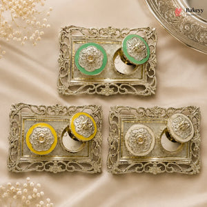 Decorative metal boxes with green and yellow accents on a beige fabric background