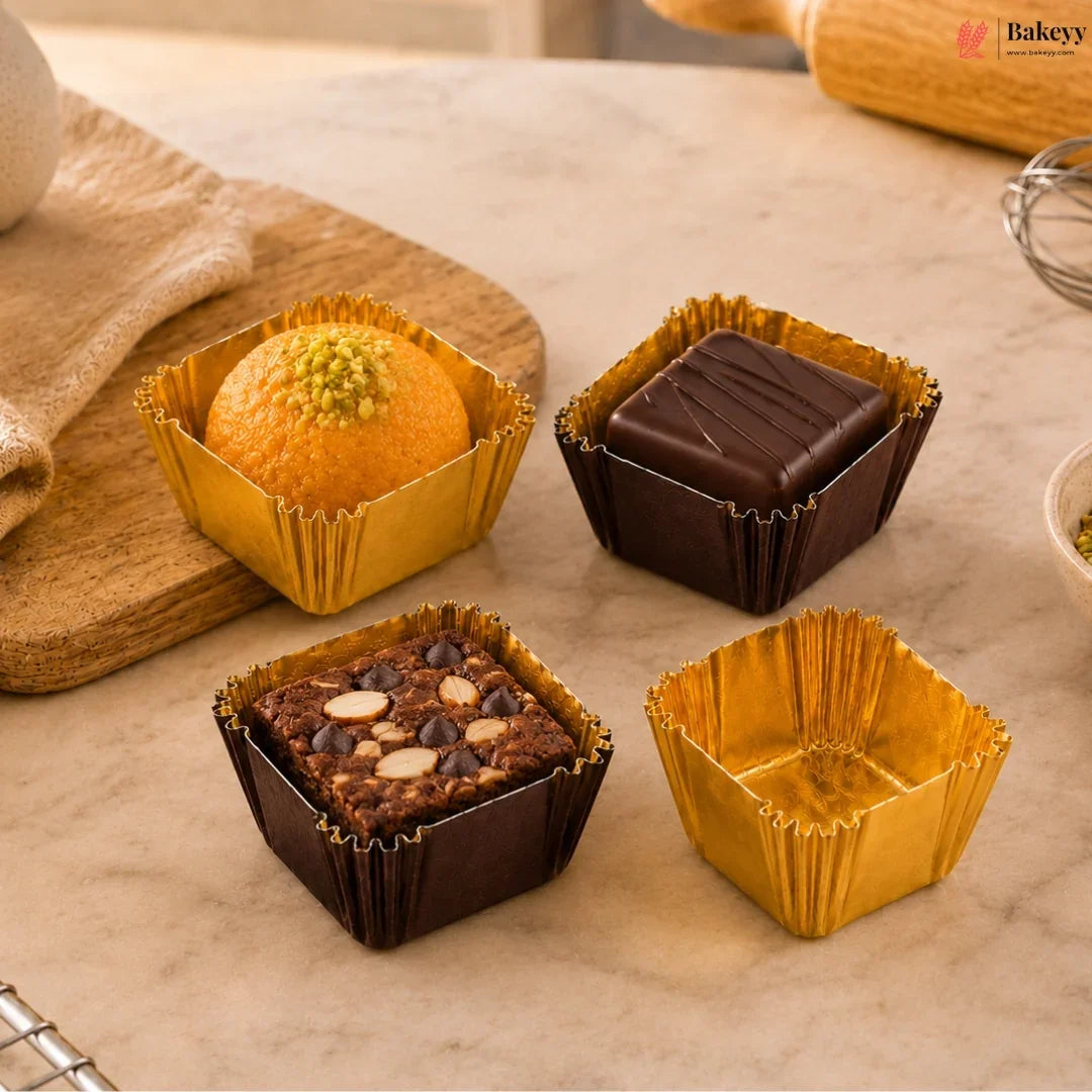 Four cupcakes in gold and brown cupcake liners on a marble surface with 'Bakey' branding.