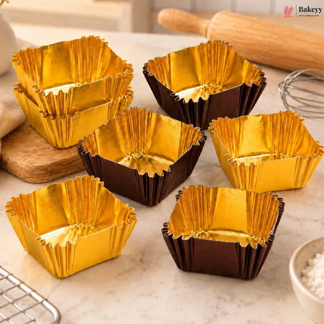 Gold and brown baking cups on a kitchen counter with a rolling pin and whisk in the background.