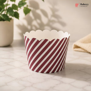 Red and white striped paper cupcake liner on a light surface with a plant in the background