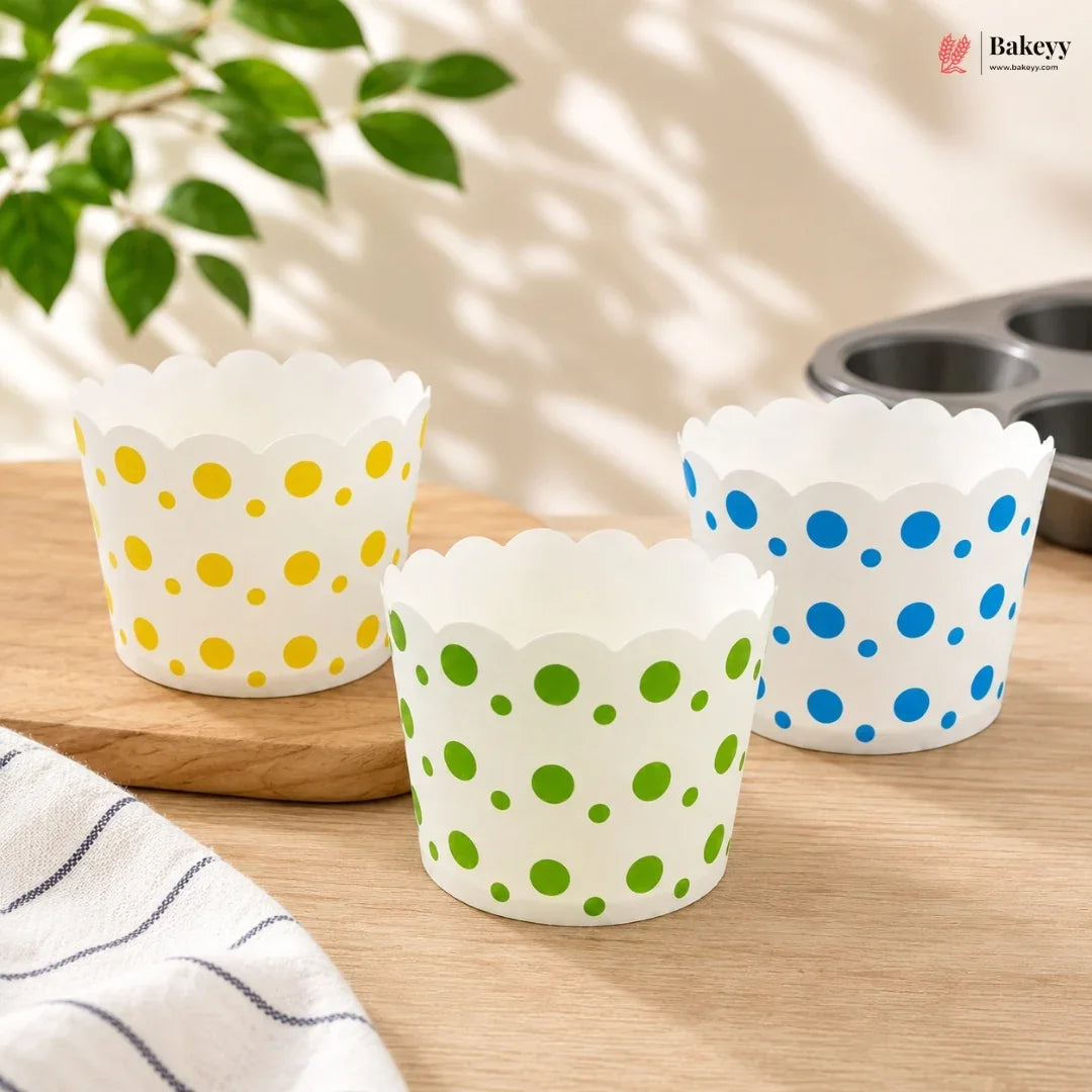 Three polka dot cupcake liners on a wooden surface with a plant in the background.
