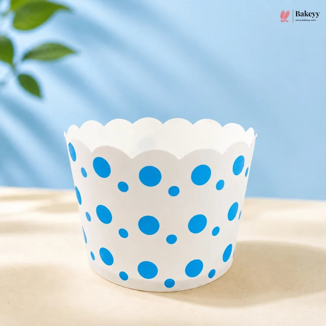 White cupcake liner with blue polka dots on a light surface with a blue background