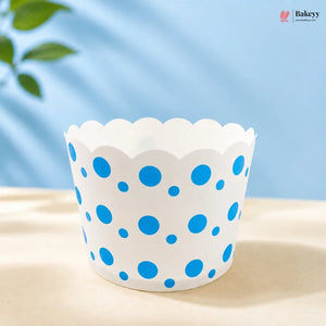 White cupcake liner with blue polka dots on a light surface with a blue background