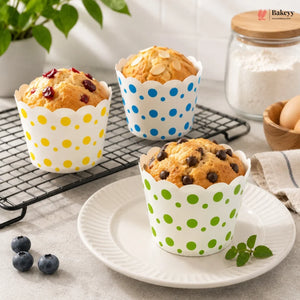 Muffins in polka dot paper cups on a plate with baking ingredients in the background.