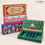 Four decorative rectangular baking boxes with intricate hand-painted traditional patterns in orange, pink, blue, and green, with one box shown open to reveal a divided interior tray compartment, set against a clean off-white background.