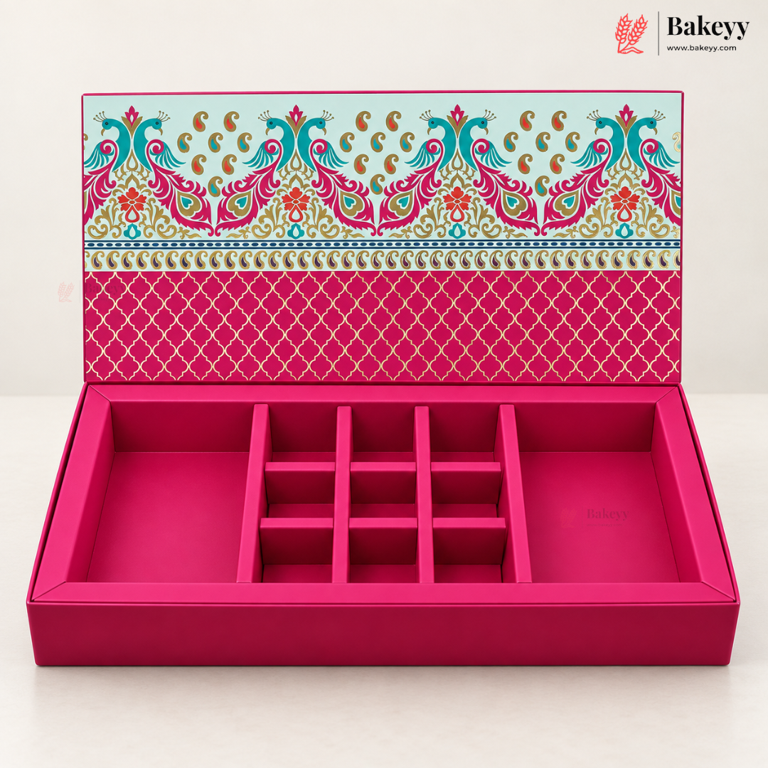 An open pink jewelry box with multiple compartments and a decorative patterned lid, photographed on a clean white background. The Bakeyy logo appears in the top right corner.