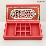 A red rectangular jewelry box with a hinged lid, shown open to reveal a nine-compartment internal organizer. The lid features an ornate, symmetrical floral pattern in red, black, and gold.