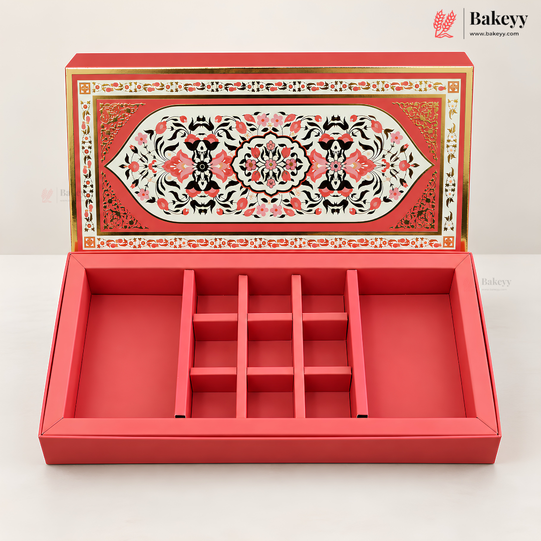 A red rectangular jewelry box with a hinged lid, shown open to reveal a nine-compartment internal organizer. The lid features an ornate, symmetrical floral pattern in red, black, and gold.