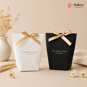 Two gift boxes, one white and one black, with gold ribbons and 'THANKYOU' text on a beige background.