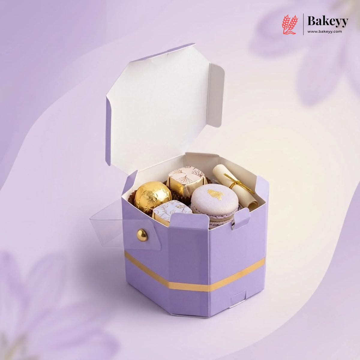 Hexagonal purple gift box with gold accents containing pastries on a light purple background, featuring the Bakeyy brand.