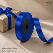 A roll of royal blue satin ribbon with a matching bow on a brown kraft paper gift box, set against a neutral beige background. Text overlays specify the width as 1/2 inch (1.