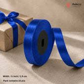 A roll of royal blue satin ribbon with a matching bow on a brown kraft paper gift box, set against a neutral beige background. Text overlays specify the width as 1/2 inch (1.