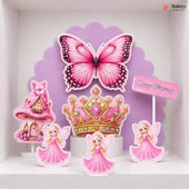 A set of pink fairy-themed birthday cake toppers displayed on a white shelf against a purple scalloped backdrop. The set includes a large pink butterfly, a pink and gold tiara, three fairy figures in pink dresses, a pink castle, and a small 'Happy Birthday' sign.