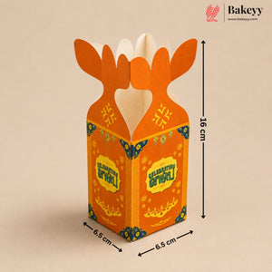An orange cardboard gift box with a festive Golu design, featuring antler-like tabs at the top, decorated with yellow and blue patterns. The image includes dimension markings showing 16 cm height and 6.