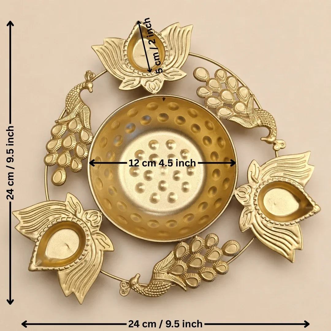 Gold-toned brass Diya holder with peacock and lotus motifs, shown with dimension markings indicating a height and width of 24 cm (9.5 inches) and a central diameter of 12 cm (4.