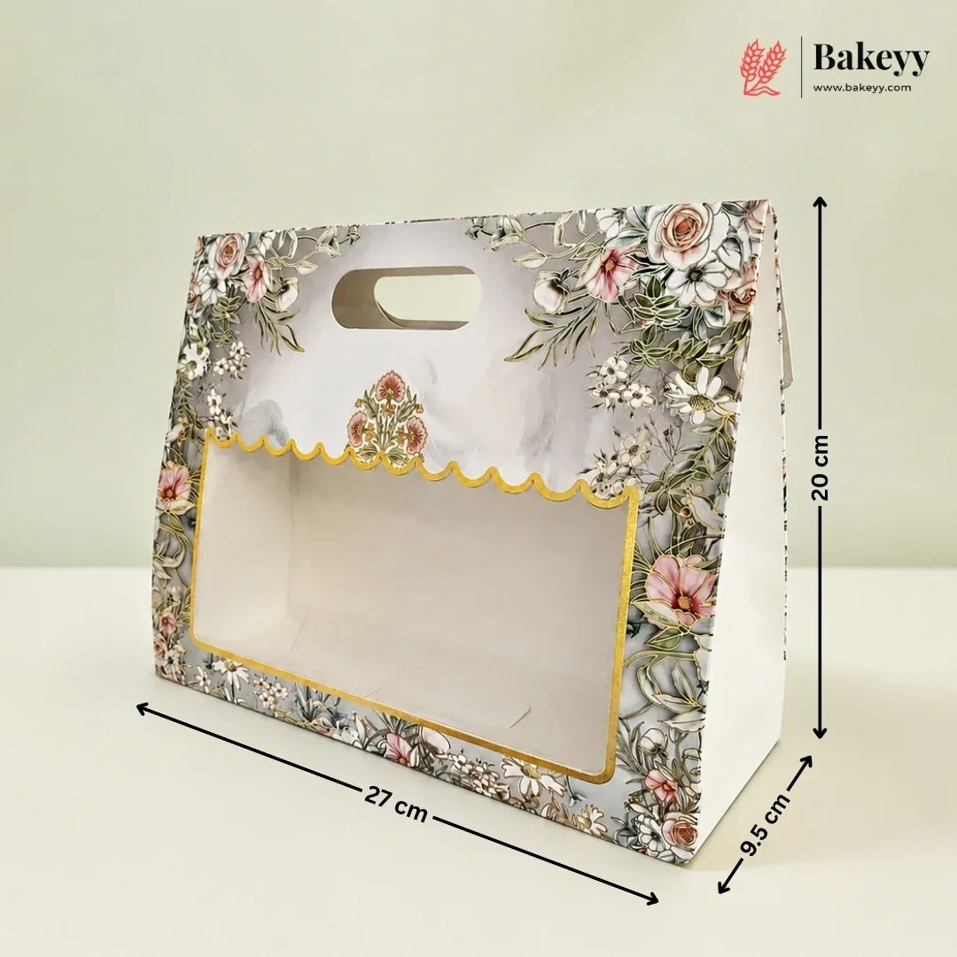 A floral bakery gift box with a clear window and scalloped gold trim, shown with dimension lines indicating 27 cm length, 20 cm height, and 9.5 cm width on a light background.