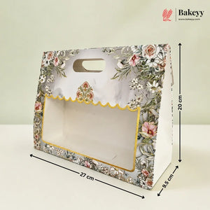 A floral bakery gift box with a clear window and scalloped gold trim, shown with dimension lines indicating 27 cm length, 20 cm height, and 9.5 cm width on a light background.