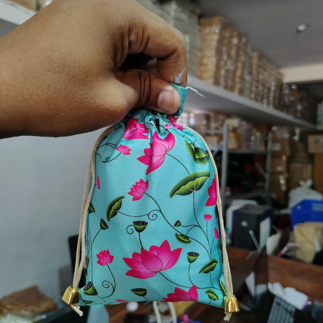 Hand holding a drawstring bag with floral design in a store setting