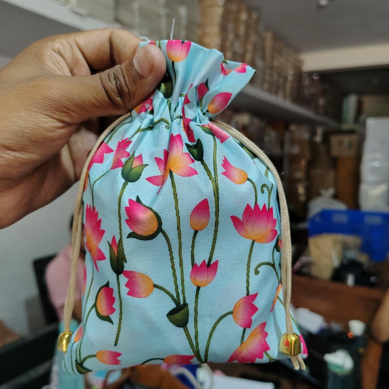 Hand holding a drawstring bag with floral pattern in a kitchen setting