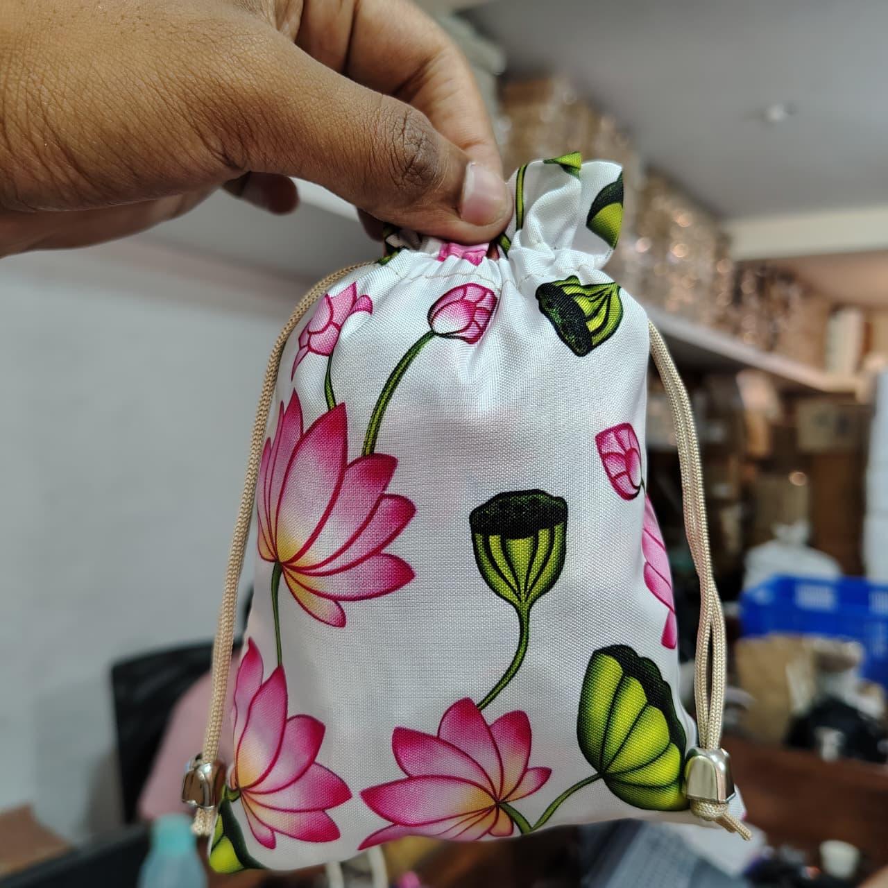 Floral drawstring bag held by a hand with a blurred background