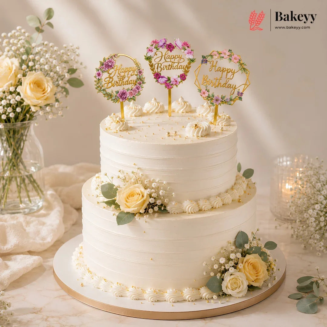 White birthday cake with floral decorations and 'Happy Birthday' toppers on a light background.