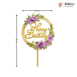 Gold 'Happy Birthday' cake topper with purple flowers and green leaves, shown with dimensions and the Bakeyy brand logo.
