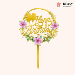 Gold birthday cake topper with pink flowers and 'Happy Birthday' text on a white background, featuring the brand 'Bakeyy'.