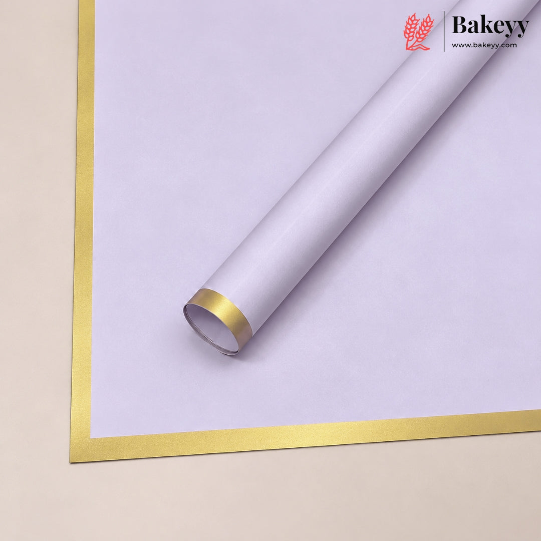 A roll of light lavender-purple wrapping paper with a metallic gold border, shown on a beige background. The brand logo 'Bakeyy' is visible in the top right corner.