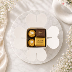 Box of Lindt Excellence chocolates on a marble surface with white flowers.