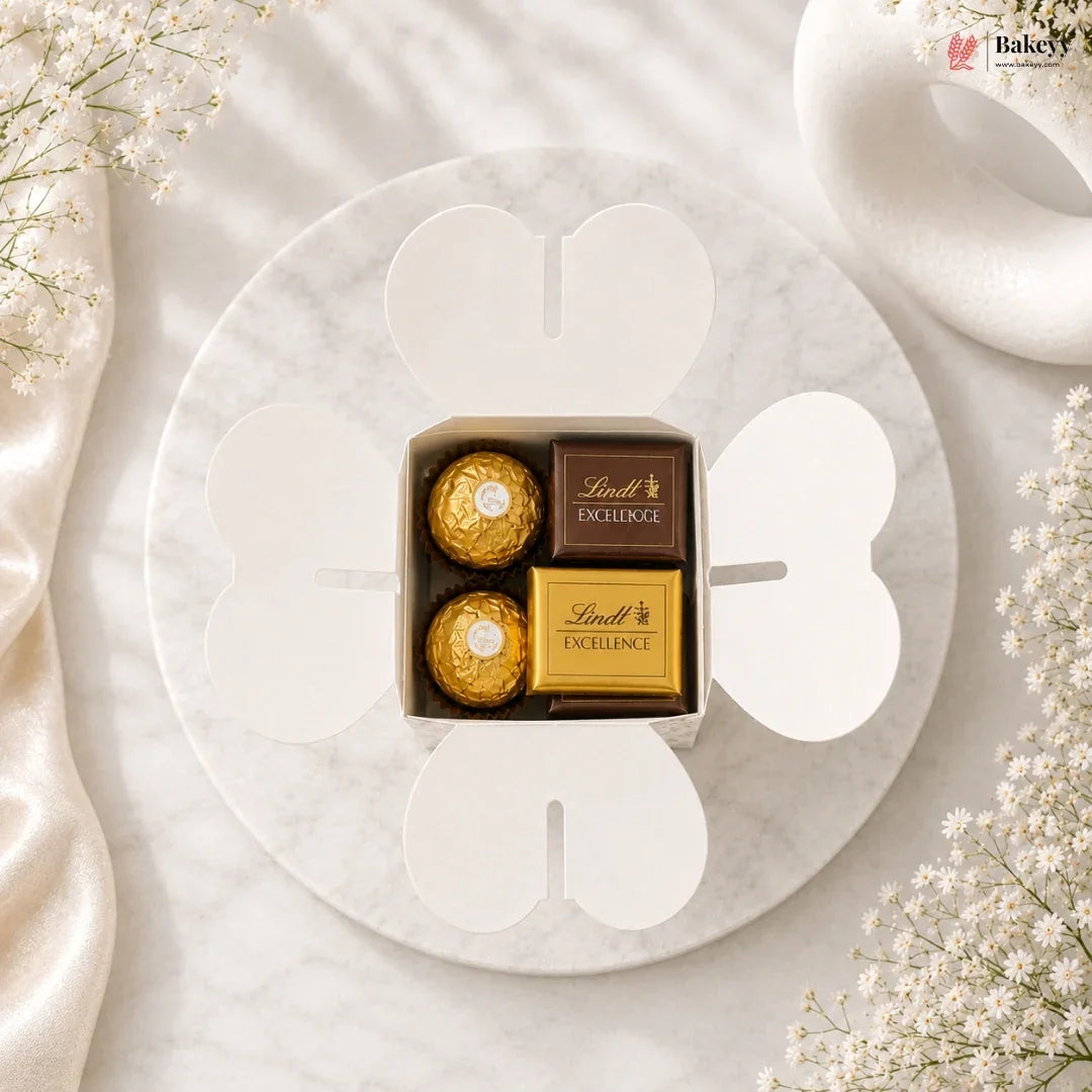 Box of Lindt Excellence chocolates on a marble surface with white flowers.