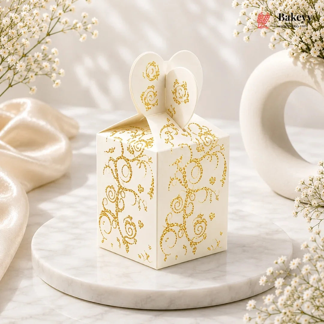 Decorative white box with gold patterns on a marble surface with flowers.