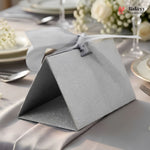 Silver gift box with a bow on a table setting with flowers and cutlery.