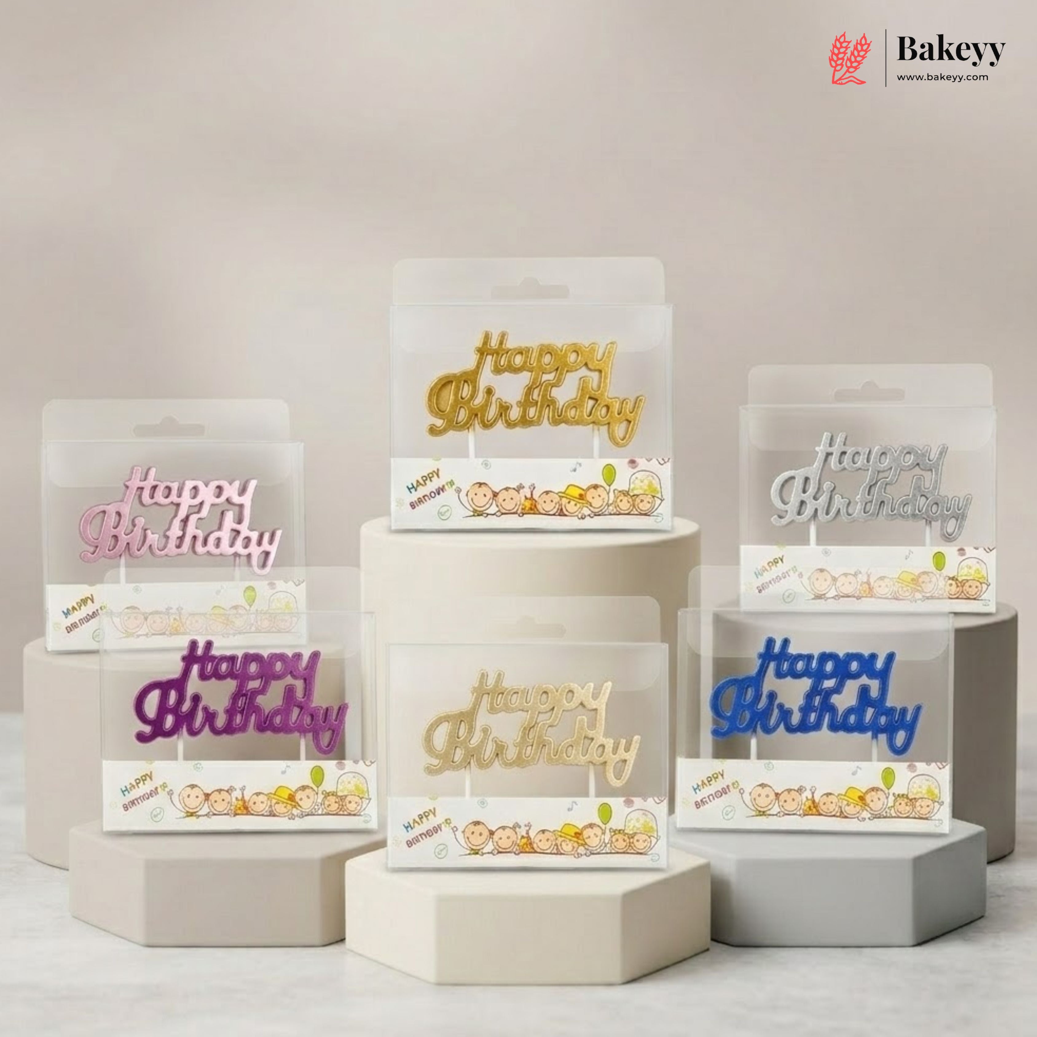 Set of 'Happy Birthday' cake toppers on display stands with 'Bakeyy' branding.