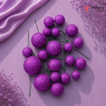 Purple glittery spherical flowers on a pink fabric background with 'Bakeyy' branding.