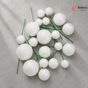 White spherical decorations on green stems with Bakeyy logo in the corner